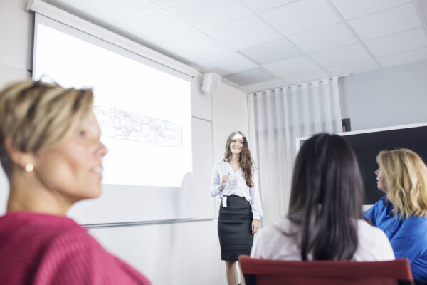 Confident woman presenting to an attentive audience in a seminar.